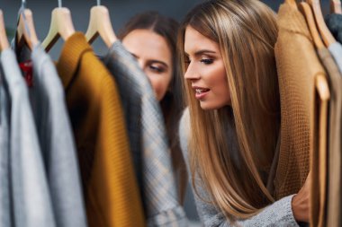 Yetişkin kadınlar sonbaharda butikte kıyafet alışverişi yapıyor.