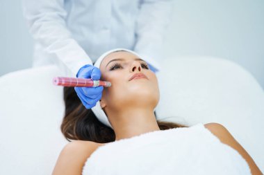 Güzel genç bir kadın güzellik salonunda yüz bakımı yaptırıyor..