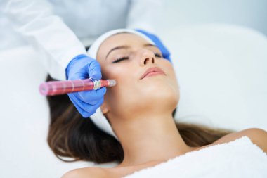 Güzel genç bir kadın güzellik salonunda yüz bakımı yaptırıyor..