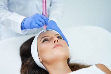 Güzel genç bir kadın güzellik salonunda yüz bakımı yaptırıyor..