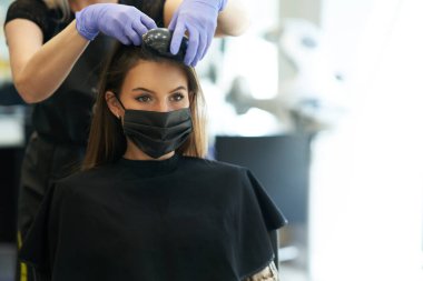 Kuaförde koronavirüs salgınından dolayı koruyucu maske takan yetişkin bir kadın.