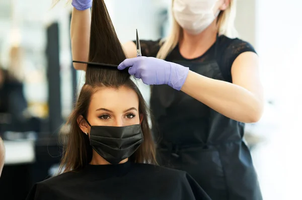 Взрослая женщина в парикмахерской в защитной маске из-за пандемии коронавируса — стоковое фото