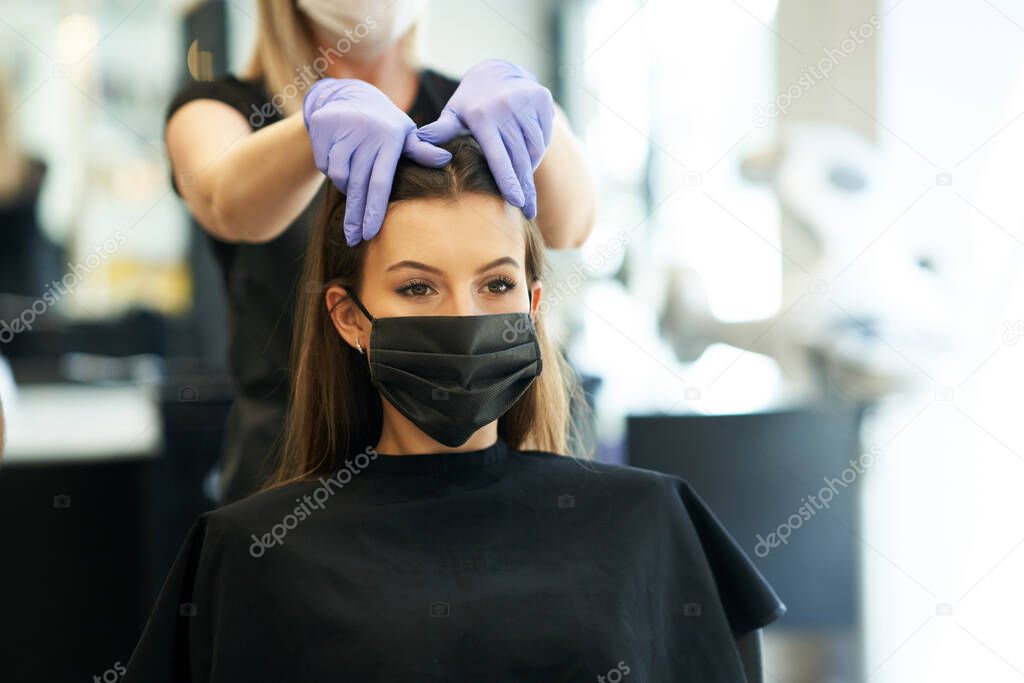 Adult woman at hairdresser wearing protective mask due to coronavirus pandemic