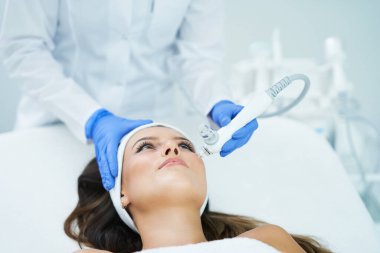 Güzel genç bir kadın güzellik salonunda yüz bakımı yaptırıyor..