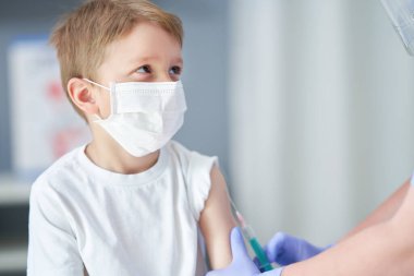 Doktor muayenehanesinde aşı olan sevimli küçük bir çocuğun portresi.