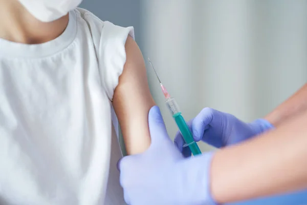 Portræt af sød lille dreng bliver vaccineret på læger kontor Stock-billede