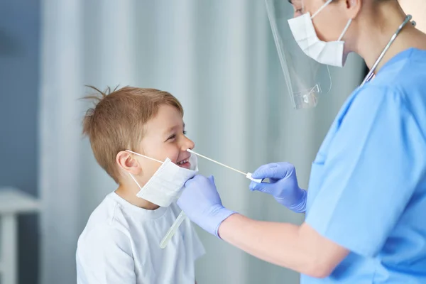 Portret van een dokter die een uitstrijkje van een jongen neemt — Stockfoto