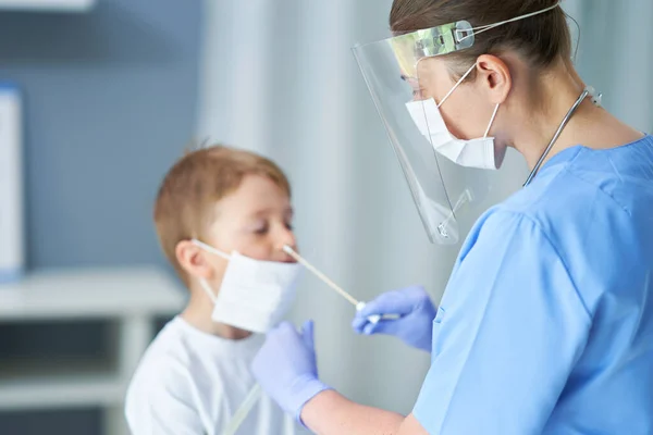 Portrait of a doctor taking a swab from a boy — Stock Photo, Image