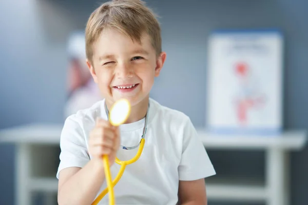 Маленький доктор со стетоскопом улыбается в кабинете врача — стоковое фото