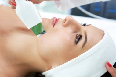 Güzel genç bir kadın güzellik salonunda yüz bakımı yaptırıyor..