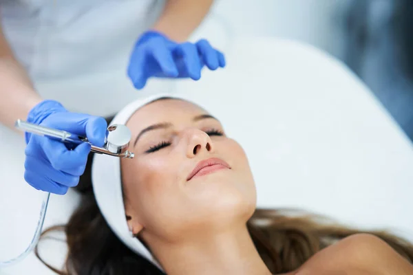 Hermosa mujer joven recibiendo tratamiento facial en el salón de belleza . — Foto de Stock