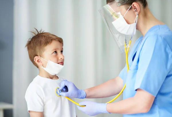 Porträt eines entzückenden kleinen Jungen, der vom Arzt mit Stethoskop getestet wird — Stockfoto