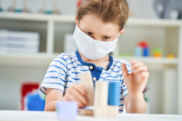 Adorable niño en el jardín de infantes con máscara debido a la pandemia de coronavirus —  Fotos de Stock