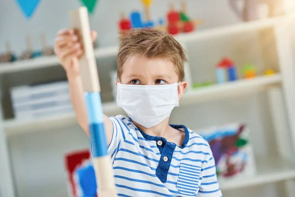 Roztomilý chlapeček ve školce s maskou na sobě kvůli pandemii koronaviru — Stock fotografie