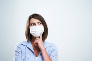 Beyaz arka planda izole edilmiş koruyucu maske takan çekici kadın.