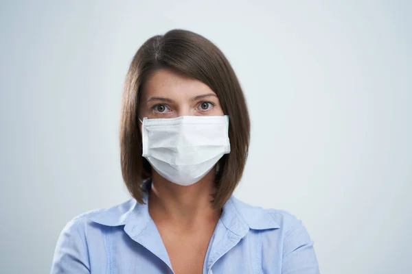 Atraktivní žena nosí ochrannou masku izolované přes bílé pozadí — Stock fotografie