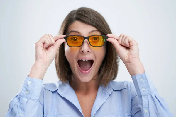 Atraktivní žena na sobě žluté modré blokovací brýle izolované přes bílé pozadí — Stock fotografie