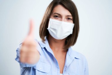 Beyaz arka planda izole edilmiş koruyucu maske takan çekici kadın.