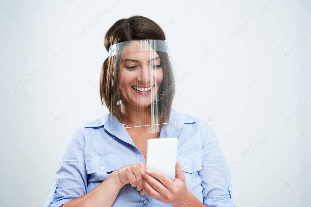 Woman wearing protective mask holding smartphone over white background