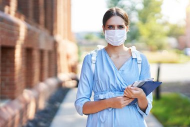 Coronavirüs salgınından dolayı maskeli bir kız öğrenci kampüste.