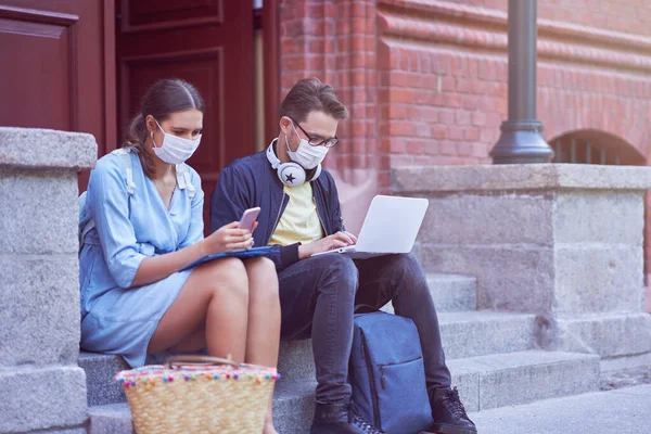 Casal de estudantes no campus usando máscaras devido a pandemia de coronavírus — Fotografia de Stock