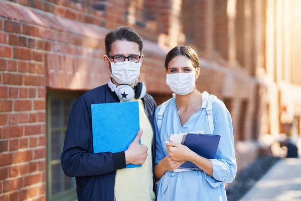 Casal de estudantes no campus usando máscaras devido a pandemia de coronavírus — Fotografia de Stock