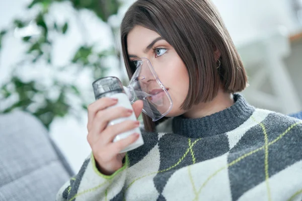 Tonåring med en inhalator i vardagsrummet — Stockfoto