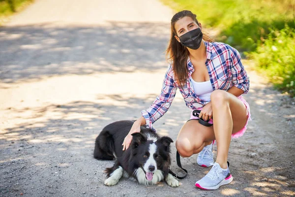 Yetişkin bir kadının evcil hayvanıyla gezdiği ve maske taktığı bir resim. — Stok fotoğraf