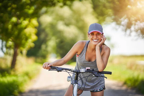 Jovem mulher feliz em uma bicicleta no campo — Fotografia de Stock