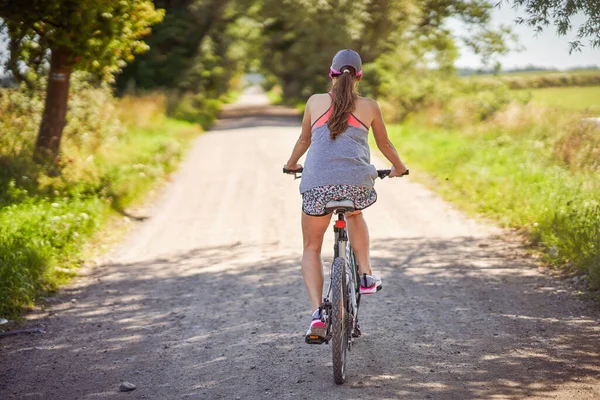 Młoda szczęśliwa kobieta na rowerze na wsi — Zdjęcie stockowe