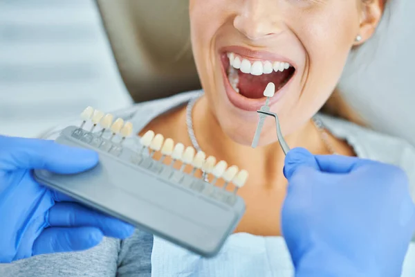 Male dentist and woman choosing tooth shade in dentist office — Stock Photo, Image