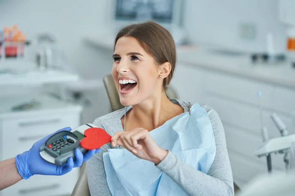 Volwassen vrouw betaalt voor bezoek in tandartspraktijk — Stockfoto