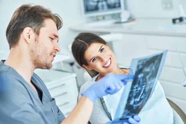 Dentista masculino e mulher discutindo resultados de raios-x em consultório odontológico — Fotografia de Stock