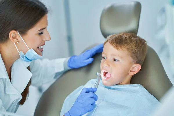 Kleine jongen en vrouwelijke tandarts in het tandartspraktijk — Stockfoto