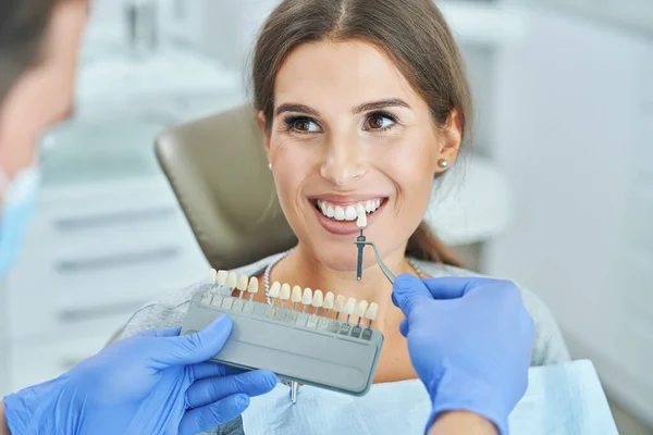 Male dentist and woman choosing tooth shade in dentist office — Stock Photo, Image