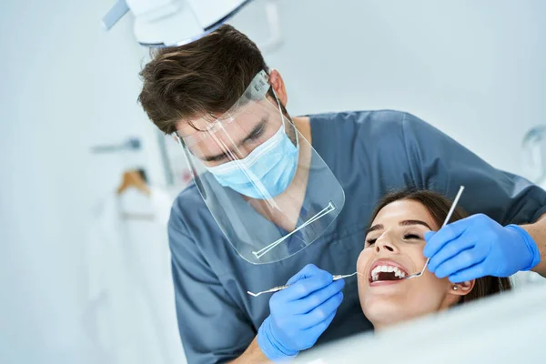 Mandlig tandlæge og kvinde i tandlæge kontor - Stock-foto