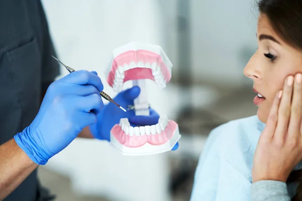 Male dentist showing jaw to woman in dentist office — Stock Photo, Image