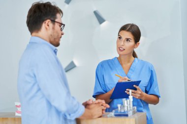 Diş kliniğinde hasta belgeleri imzalıyor.