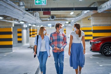 Bir grup koruma maskeli genç yeraltı otoparkında