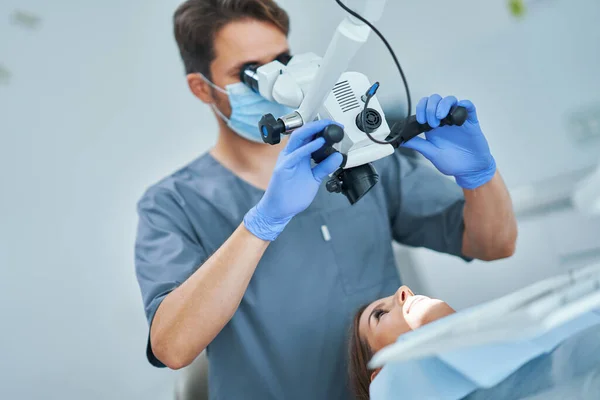 Tandarts controleren patiënt tanden met microscoop op kantoor chirurgie — Stockfoto