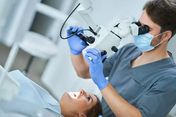 Dentista revisando los dientes del paciente con microscopio en el consultorio de cirugía — Foto de Stock