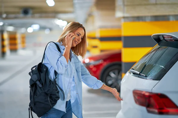 Mujer adulta usando el teléfono celular en el estacionamiento subterráneo —  Fotos de Stock