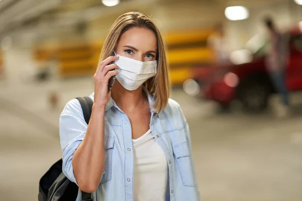 Adult woman in protection mask using cellphone in underground parking lot — Stock Photo, Image