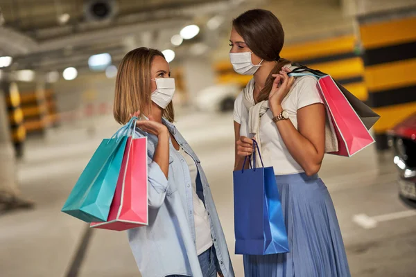 Duas mulheres com sacos de compras em máscaras no estacionamento subterrâneo — Fotografia de Stock