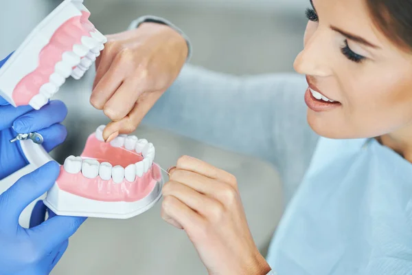 Dentista masculino mostrando mandíbula para mulher no consultório odontológico — Fotografia de Stock