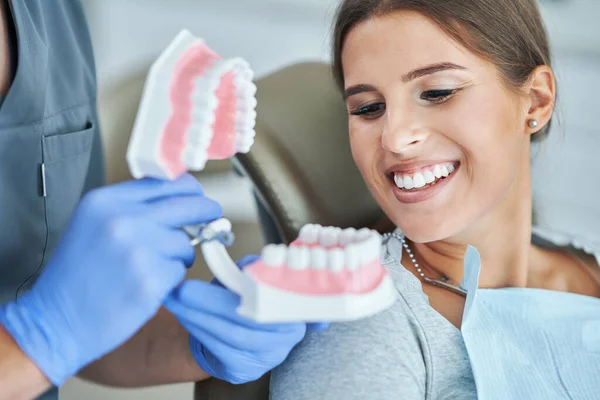Mand tandlæge viser kæbe til kvinde i tandlæge kontor - Stock-foto