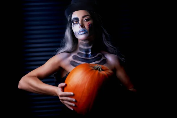 Retrato assustador de mulher em halloween maquiagem gótica segurando abóbora — Fotografia de Stock