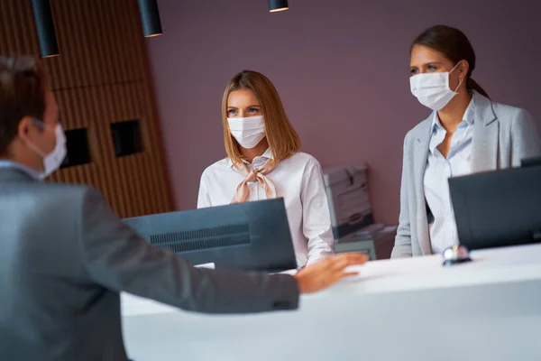 Egy maszkos üzletember bejelentkezik egy hotel recepciójára. — Stock Fotó