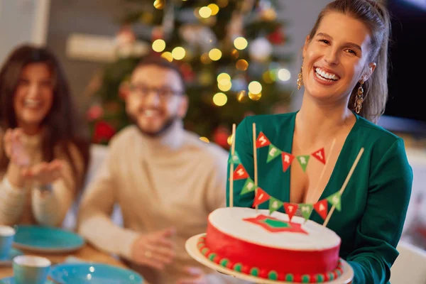 Baráti társaság ünnepli otthon a karácsonyt puccos tortával — Stock Fotó