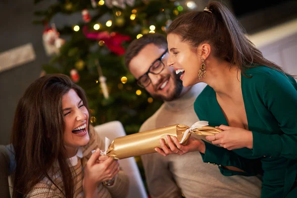 Group of friends celebrating Christmas by pulling crackers — Stock Photo, Image